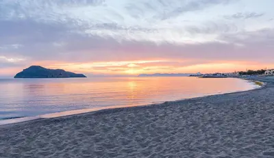 a view of a beach with a sunset in the background at Porto Platanias - Casa Di Porto in Plataniás