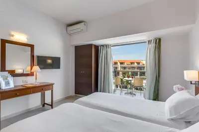 a hotel room with two beds and a window at Porto Platanias - Casa Di Porto in Plataniás