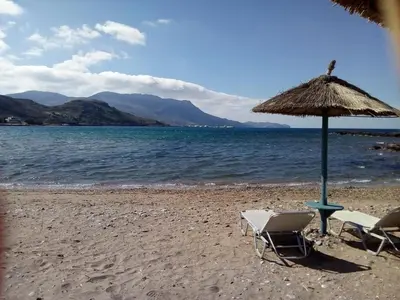 two chairs and an umbrella on a beach at Kissamos Nice Apartment1 in Kissamos