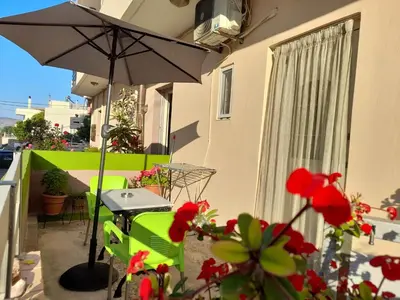a patio with a table and an umbrella and flowers at Kissamos Nice Apartment1 in Kissamos