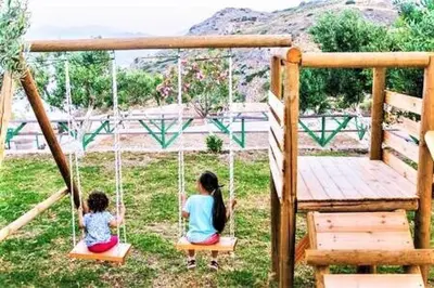 two children sitting on a swing in a yard at Villa Akrolithos with Private Pool in Chania Town
