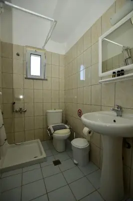 a bathroom with a sink and a toilet and a mirror at KOYNTOYRA ROOMS in Kountoura Selino