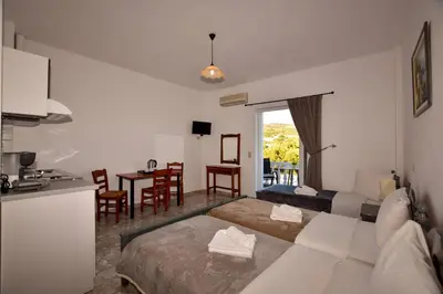 a living room with a bed and a table with chairs at KOYNTOYRA ROOMS in Kountoura Selino