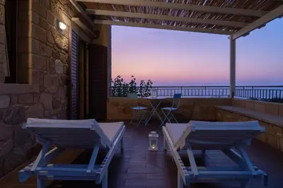 a patio with chairs and a table on a balcony at Sunset Villas in Falasarna
