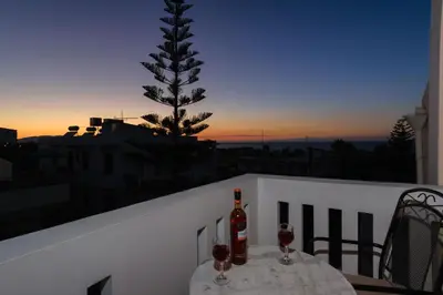 a table with wine glasses and a tree on a balcony at Marianthi's Maisonette in Chania Town