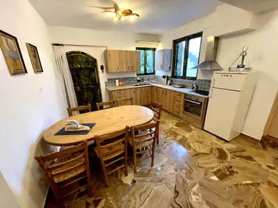 a kitchen with a wooden table with chairs and a refrigerator at Village Villa Mimis Drapanias in Drapaniás