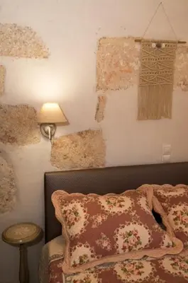 a bedroom with a bed and a lamp and a wall at Iliopetra Villa in Beritianá