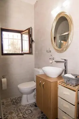 a bathroom with a toilet and a sink and a mirror at Iliopetra Villa in Beritianá