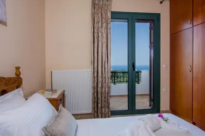 a bedroom with a bed and a view of the ocean at Hilltop Villa Kontomari in Kondomari