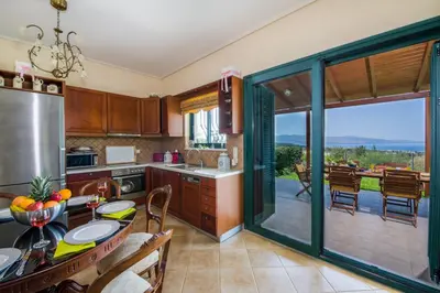 a kitchen with a table and a large sliding glass door at Hilltop Villa Kontomari in Kondomari