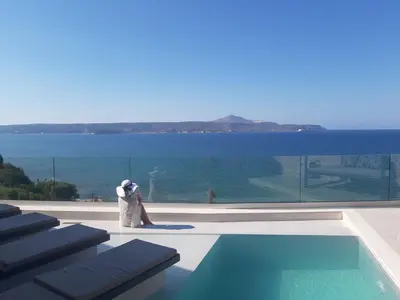 a man is standing next to a swimming pool at Luxury Villa Dioskouroi Heated eco pool & jacuzzi in Kalyves