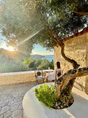 a woman sitting in a chair under a tree at Luxury Villa Dioskouroi Heated eco pool & jacuzzi in Kalyves