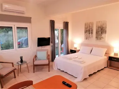 a bedroom with a white bed and a tv at Emerald Apartment 2 Halepa in Chania Town