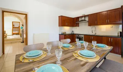 a kitchen with a wooden table with plates and glasses at Lilium Stone Villa in Varípetron