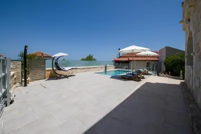 a patio with a swimming pool and a house at Lilium Stone Villa in Varípetron