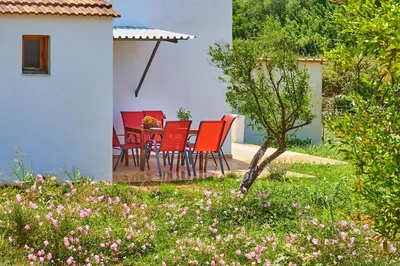 a patio with red chairs and a table in a yard at Platanos Stone House I With Shared Pool in Kalyves