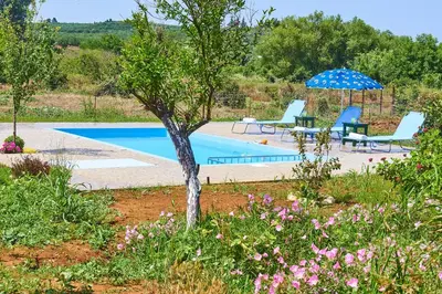 a swimming pool with two lounge chairs and an umbrella at Platanos Stone House I With Shared Pool in Kalyves