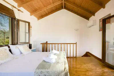a bedroom with a bed with white sheets and a window at Platanos Stone House I With Shared Pool in Kalyves
