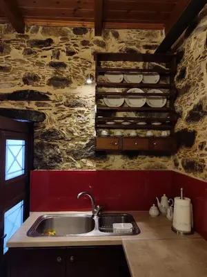 a kitchen with a sink and a stone wall at Grandma Agatha & Virginia's stonehouse in Kefálion