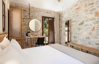 a bedroom with a bed and a desk in a stone wall at The Authentic Village Boutique Hotel in Khóra Sfakíon