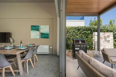 a patio with a table and chairs and a wood stove at Ethereal Villas Chania in Daratso