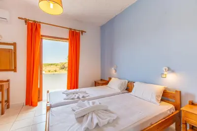 a bedroom with two beds and a window with orange curtains at Ohana in Kamisianá