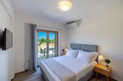 a bedroom with a bed and a balcony at Villa Persephone in Tavronitis
