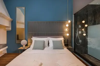 a bedroom with a large white bed with blue walls at Veneri Boutique Suites in Chania Town