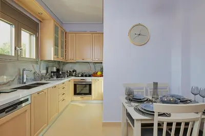 a kitchen with a table and a clock on the wall at Cypress Village - Lux villa 5' from beach in Daratso
