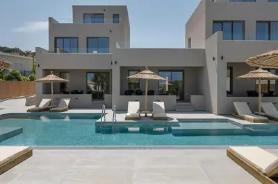 a villa with a swimming pool with chairs and umbrellas at Casa Nostos in Agia Marina Nea Kydonias