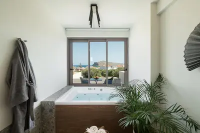 a bathroom with a soaking tub with a window at Casa Nostos in Agia Marina Nea Kydonias