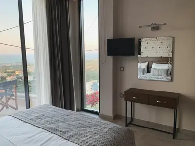 a bedroom with a bed and a large window at King Crimson Luxury Apartments in Marathokefála