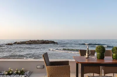 a table and chairs with a view of the ocean at Villa Seashell -Wonderful newly renovated villa on the beach in Galatás