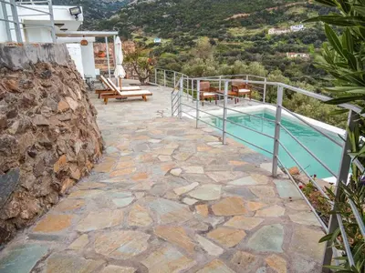 a swimming pool with a stone walkway next to a house at Kampos View - Quiet House at the end of the Road, private pool in Kámbos