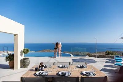 a woman standing on the edge of a patio with a table with wine glasses at Villa Thetis Sfakia in Sfakiá