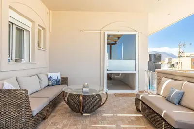 a patio with a couch and a table on a balcony at kissamos seaside bliss in Kissamos