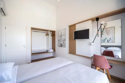 a bedroom with a bed and a mirror and a chair at Isalos Seafront Villa I Sea fragrance in Chania Town