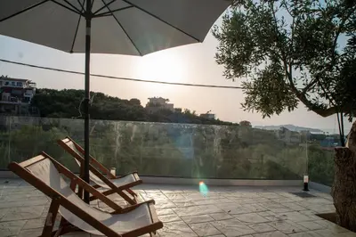 two chairs and an umbrella on a patio at Hello Village Chania in SFakianalíon