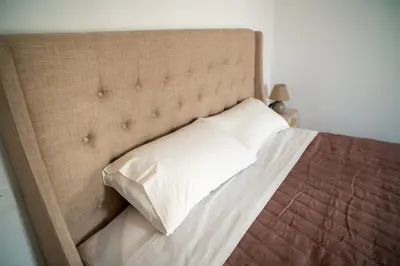 a bed with a brown headboard with a white pillow at Hello Village Chania in SFakianalíon