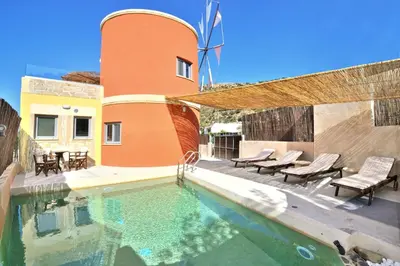 a swimming pool with chairs and a house at Anemomili Villas in Drapaniás