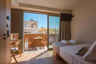 a bedroom with a bed and a balcony with a table at Thallos The Boutique in Chania Town