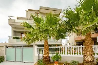 a building with palm trees in front of it at Mare Monte Luxury Apartment in Kissamos