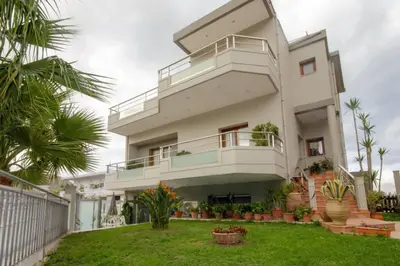 a white house with a balcony and a yard at Mare Monte Luxury Apartment in Kissamos