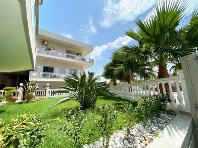 a house with a white fence and palm trees at Mare Monte Luxury Apartment in Kissamos