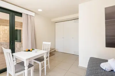 a dining room with a white table and chairs at Elia Platanias in Plataniás