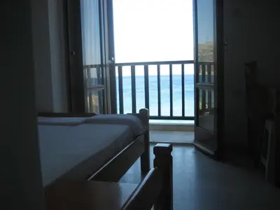a bedroom with a bed and a view of the ocean at Spamandos Rooms in Palaiochóra