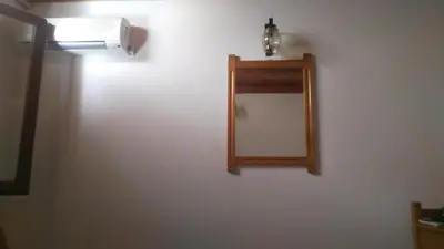 a bathroom with a mirror and a light on a wall at Spamandos Rooms in Palaiochóra