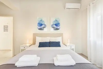 a white bedroom with a large bed with two towels at Marika's Penthouse Chania in Chania Town
