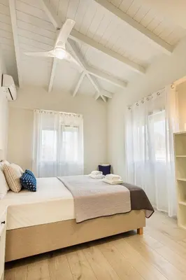a bedroom with a large bed with a ceiling fan at Marika's Penthouse Chania in Chania Town