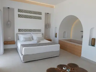 a white bedroom with a bed and a bath tub at Sfakia Seaside luxury Suites in Khóra Sfakíon